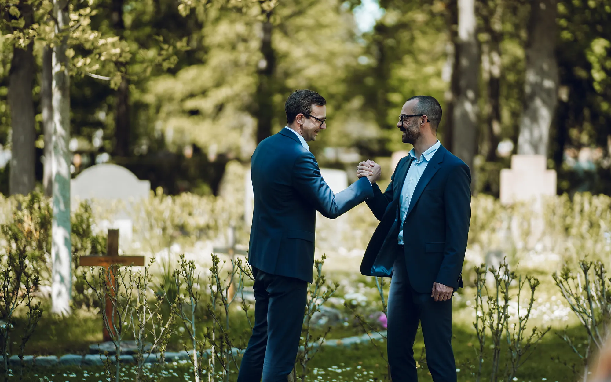 Tobias Göck und ein Kollege reichen sich auf einem Friedhof die Hand